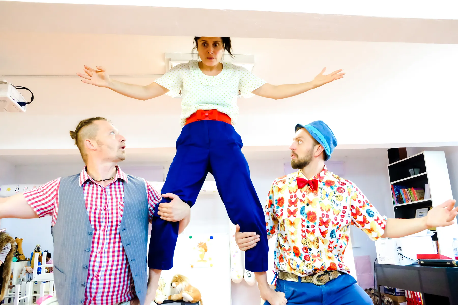 Zwei Clowns tragen eine Artistin auf ihren Händen